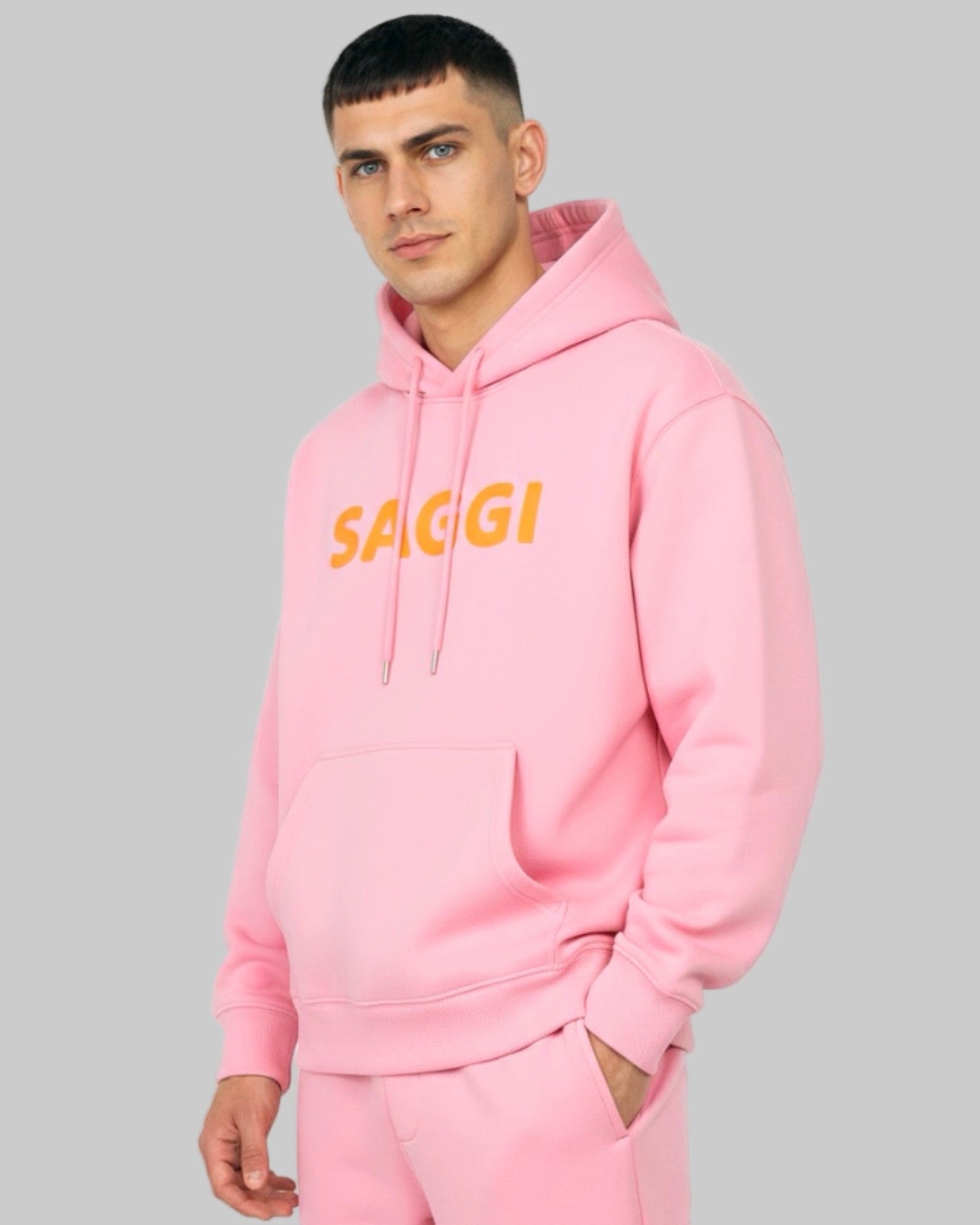 Model wearing pink SAGGI heavyweight graphic hoodie with orange logo and pink drawstrings, true-to-size fit.