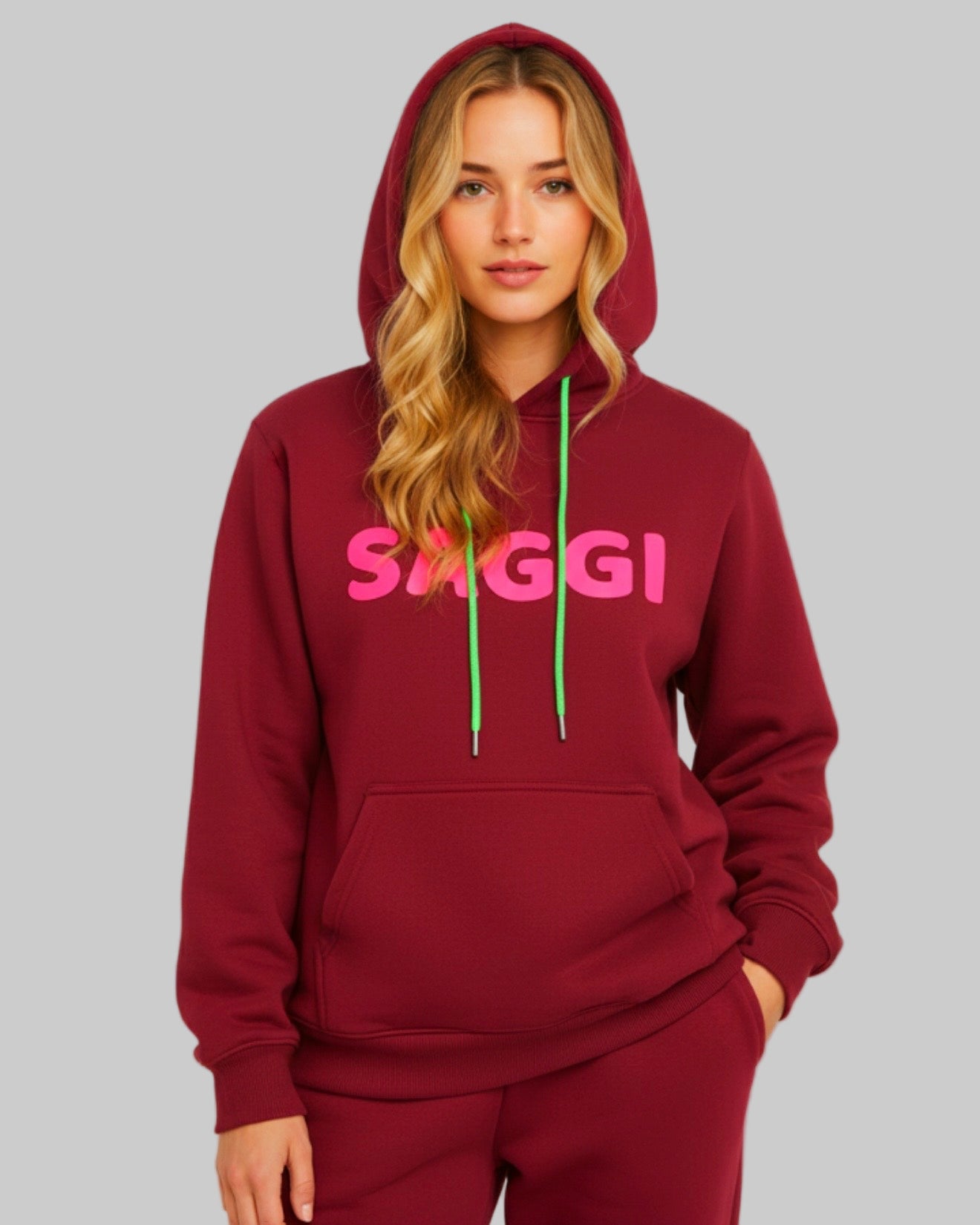 Model wearing burgundy SAGGI heavyweight graphic hoodie with fuchsia logo and green drawstrings, true-to-size fit.