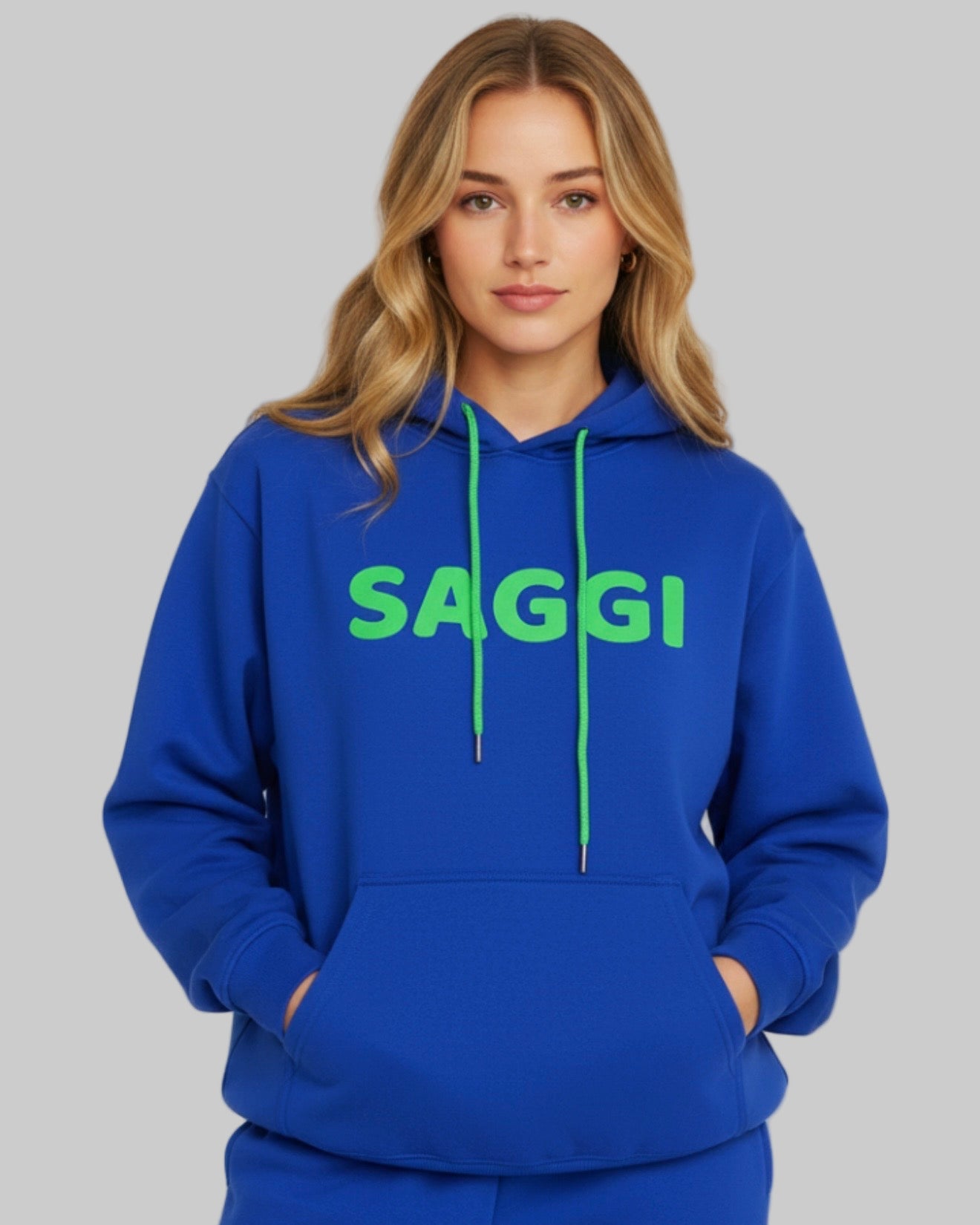 Model wearing royal blue SAGGI heavyweight graphic hoodie with green logo and green drawstrings, true-to-size fit.