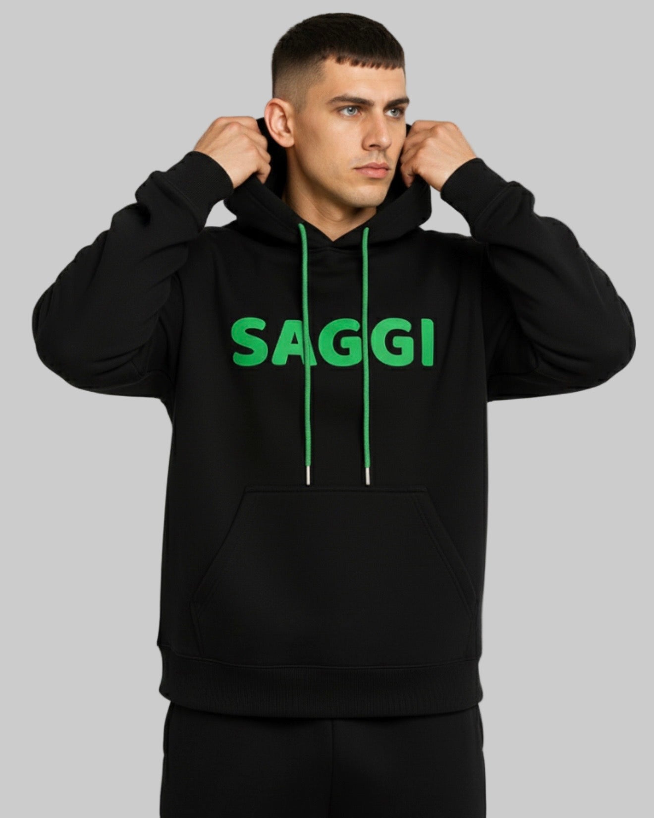 Model wearing black SAGGI heavyweight graphic hoodie with green logo and green drawstrings, true-to-size fit.