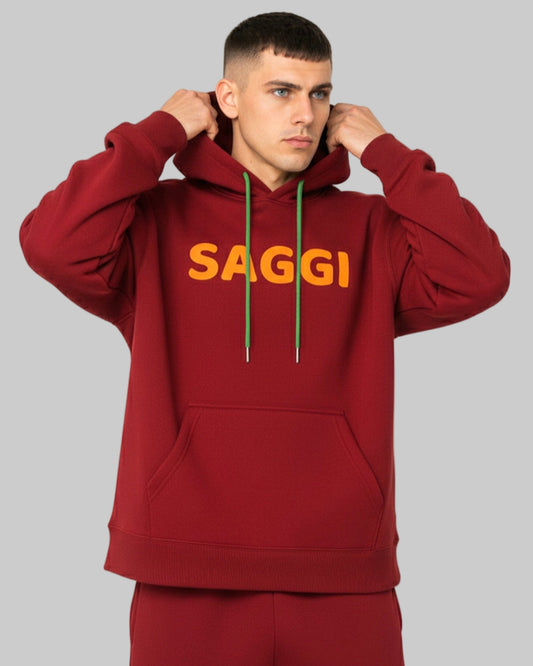 Model wearing burgundy SAGGI heavyweight graphic hoodie with orange logo and green drawstrings, true-to-size fit.