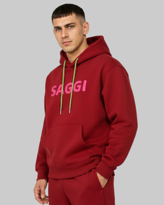 Model wearing burgundy SAGGI heavyweight graphic hoodie with fuchsia logo and green drawstrings, true-to-size fit.