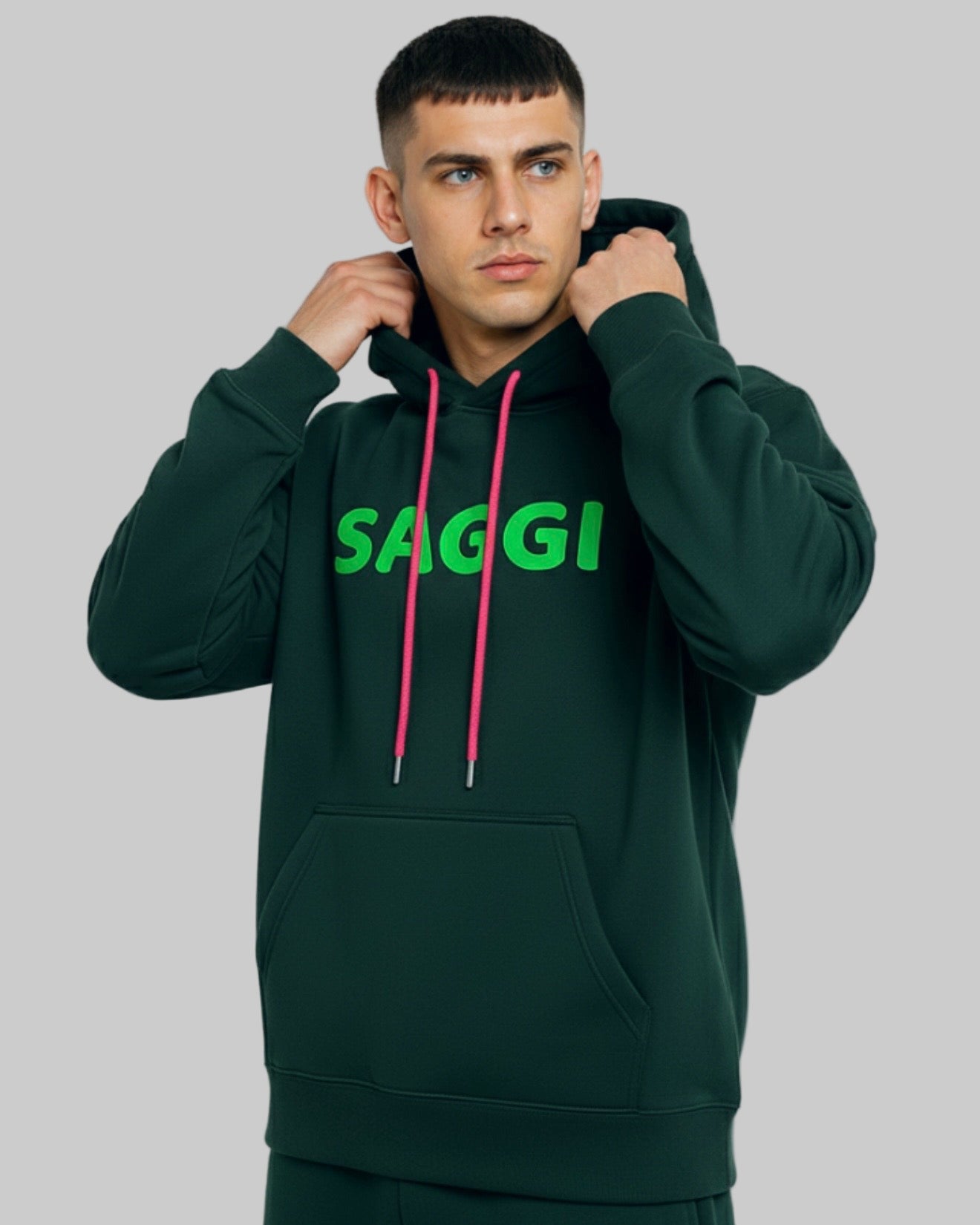 Model wearing forest green SAGGI heavyweight graphic hoodie with green logo and fuchsia drawstrings, true-to-size fit.
