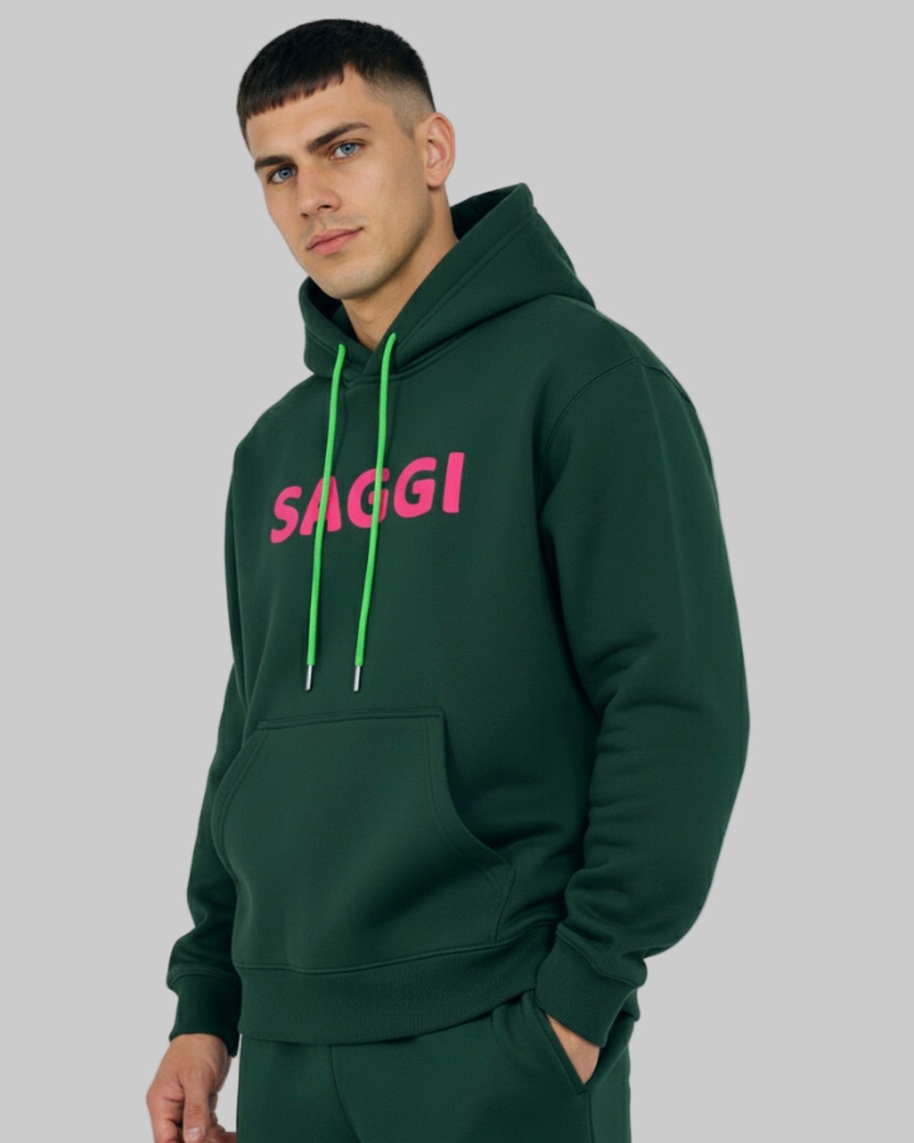 Model wearing forest green SAGGI heavyweight graphic hoodie with fuchsia logo and green drawstrings, true-to-size fit.