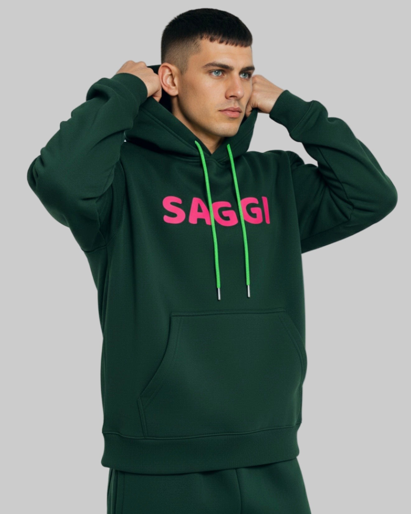 Model wearing forest green SAGGI heavyweight graphic hoodie with fuchsia logo and green drawstrings, true-to-size fit.